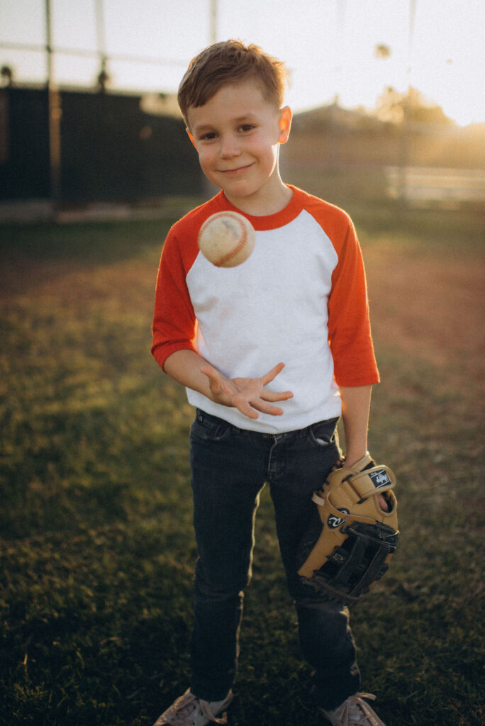 boy smiling and throwing up the ball while looking at the camera for their storytelling photo session