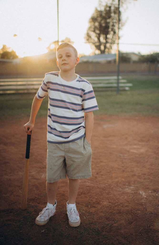 boy leaning on a bat during their