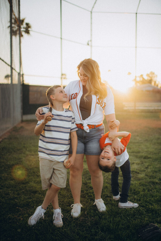 son looking up at his mom holding his bat and ball for their storytelling photo session