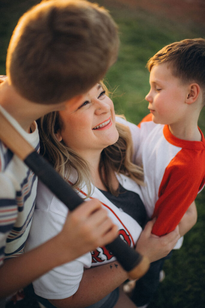 mom smiling as her boys give her a kiss