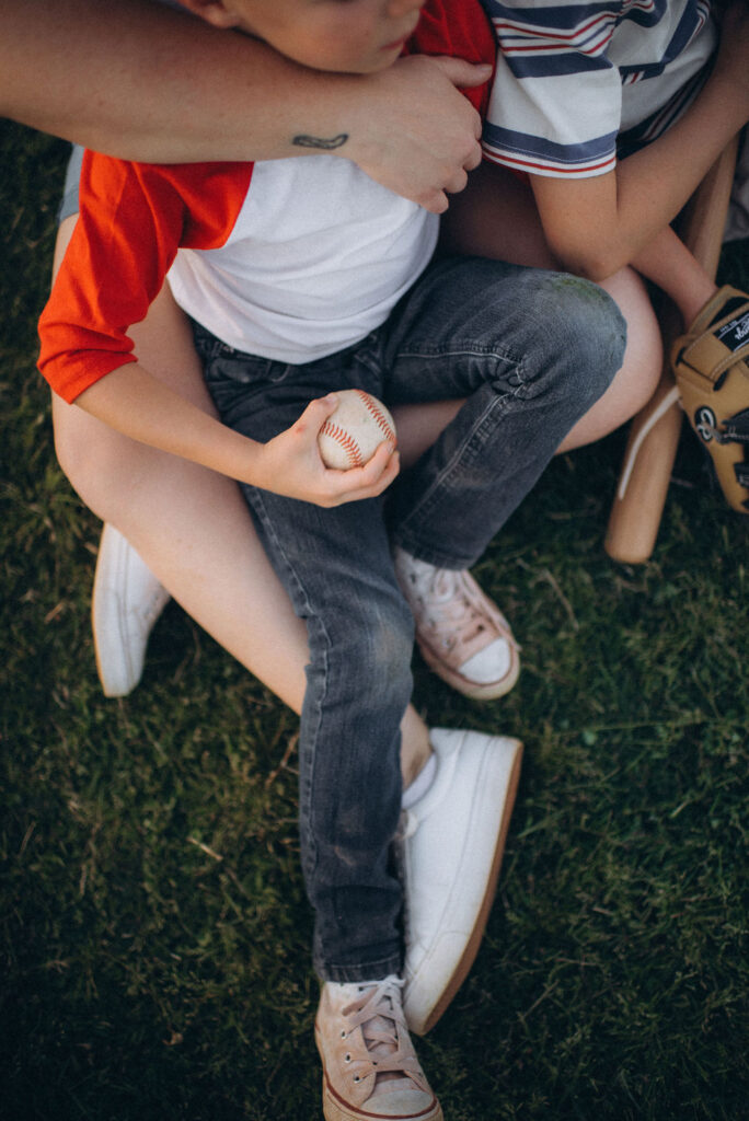 legs all strewn around while boy is holding a baseball for their storytelling photo session